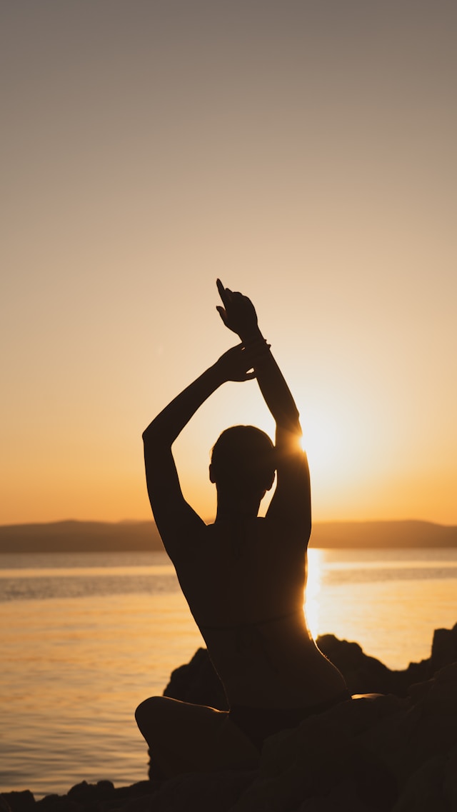 Woman doing a yoga pose with a lake and a sunset