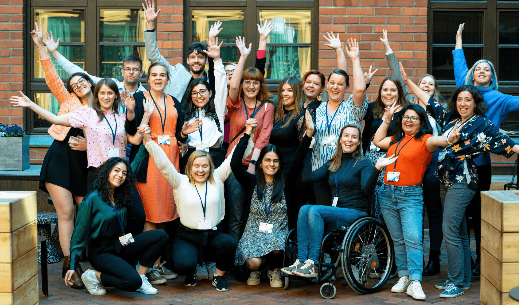 Young people with disabilities in a group cheering for a photo raising hands