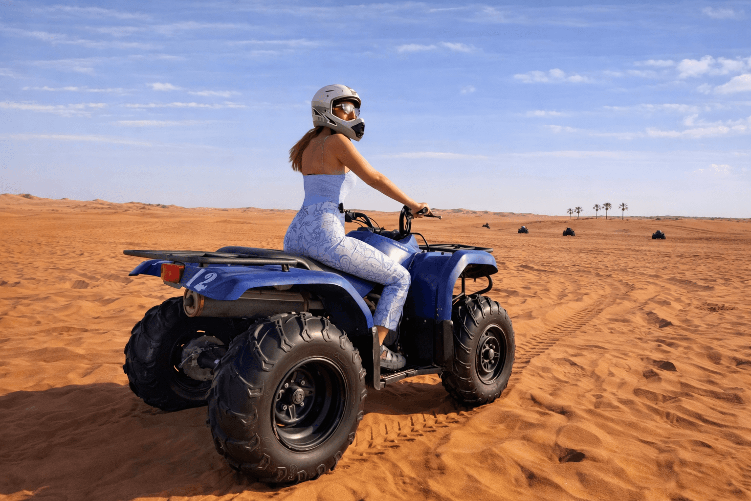 Woman riding a Yamaha 350cc ATV across the Dubai desert during a quad biking experience with Dune Quest Tours