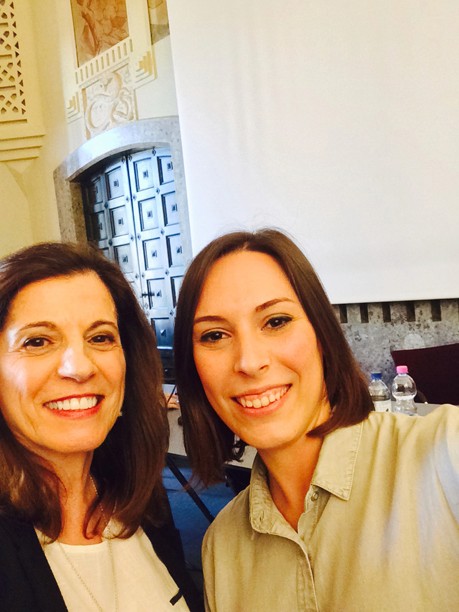 A photo of two women standing in a conference hall.