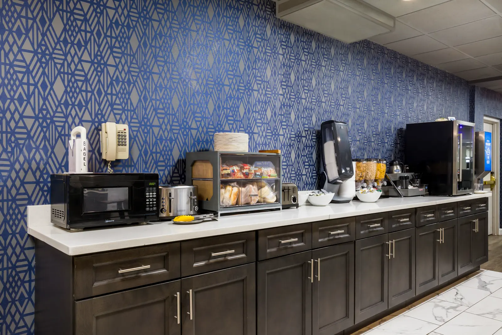 Breakfast bar with microwave, toasters, coffee, cereal, and pastries.