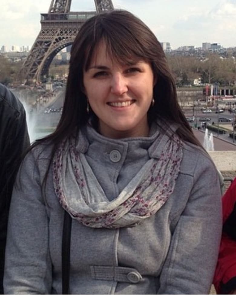 Black-and-white portrait of a man with an afro in motion, wearing a hoop earring and chain necklace, against a light gray background.