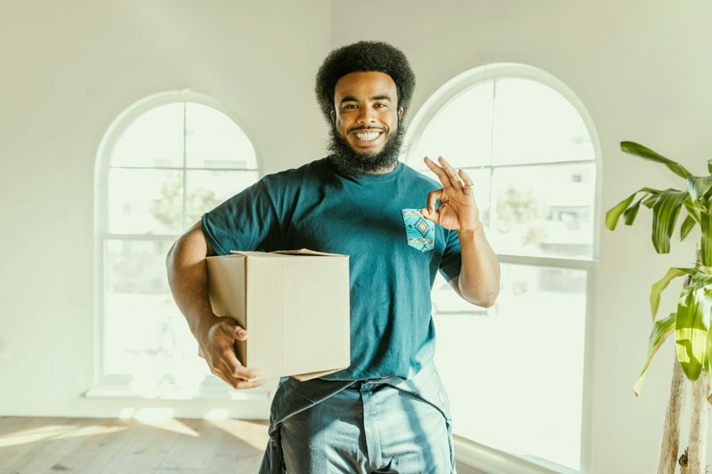 Moving Company worker holding a box and smiling to the camera.