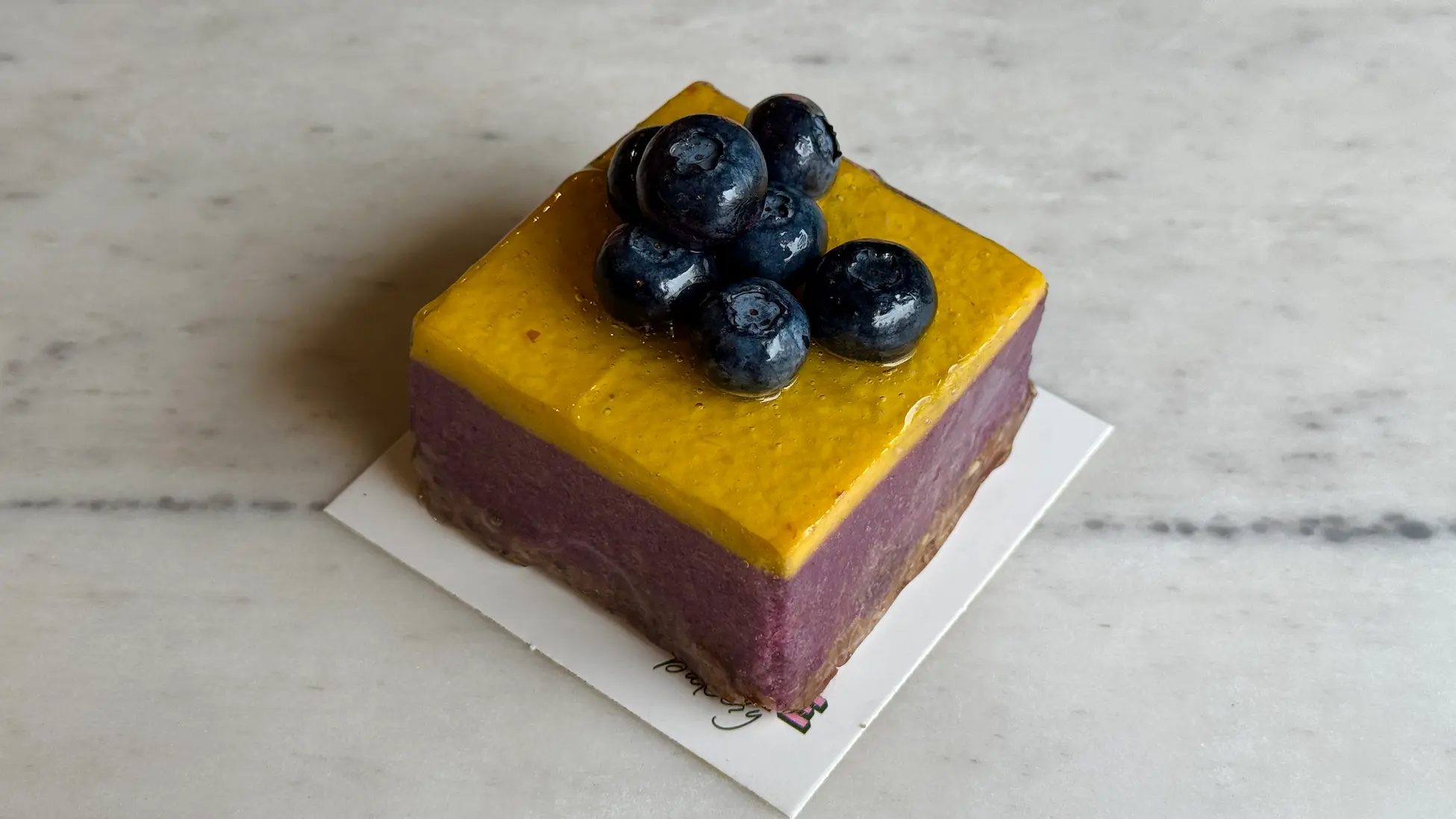Two-layer mousse cube with purple base and yellow top, garnished with fresh blueberries