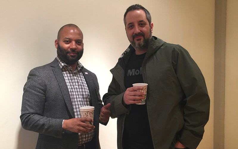 A photo of two men holding some coffee cups.