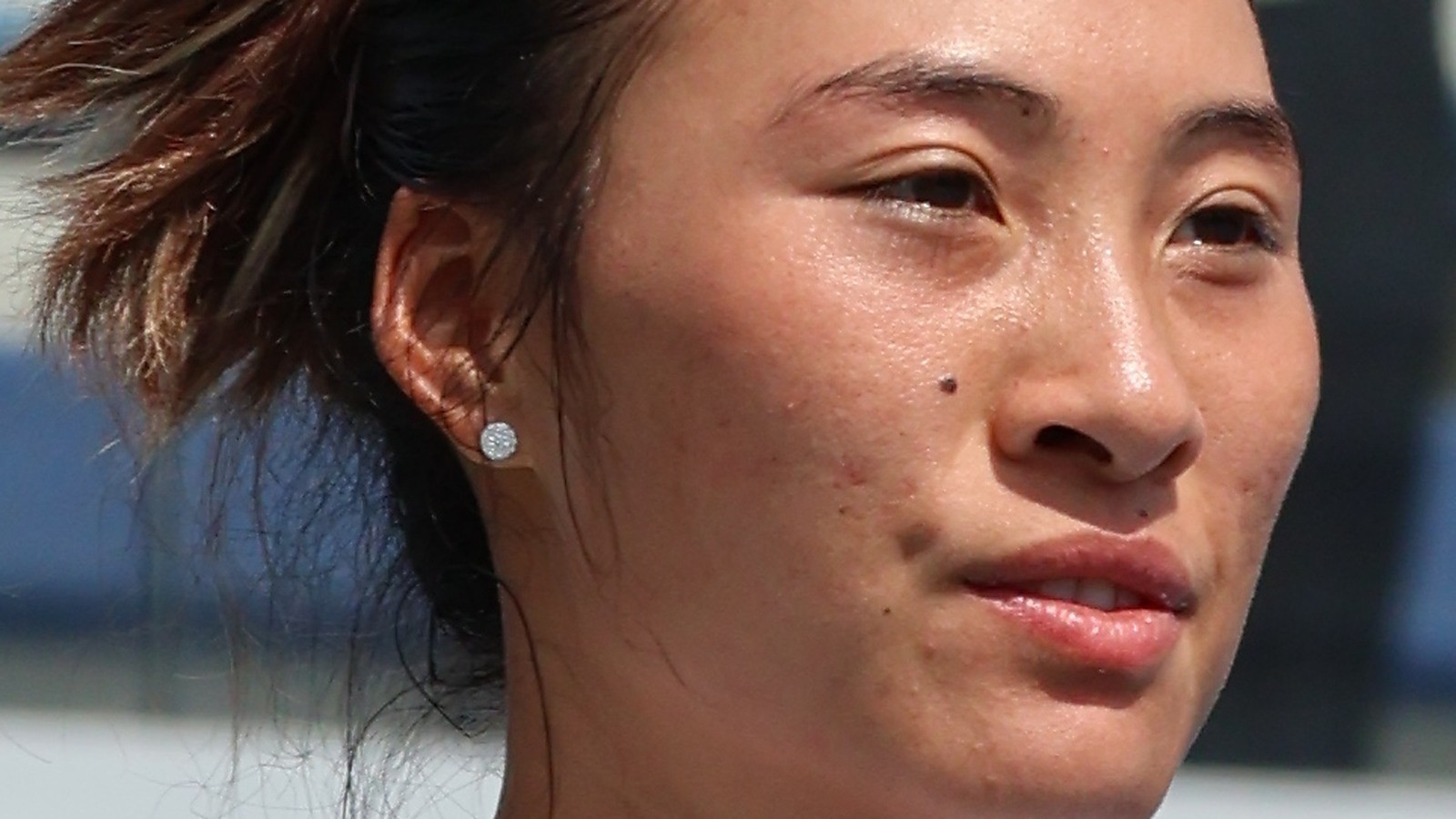 Close-up of Zheng Qinwen in a white shirt after a match, face centered
