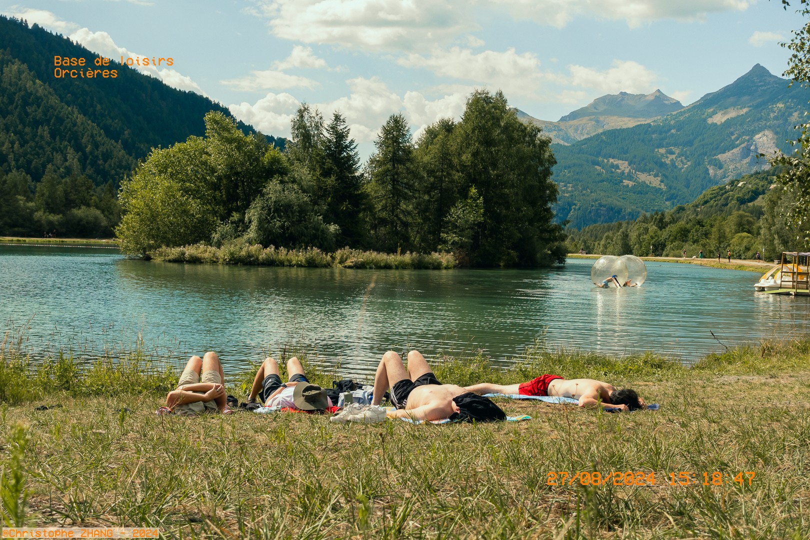 Groupe d’amis allongés sur l’herbe au bord du lac à Orcières.
