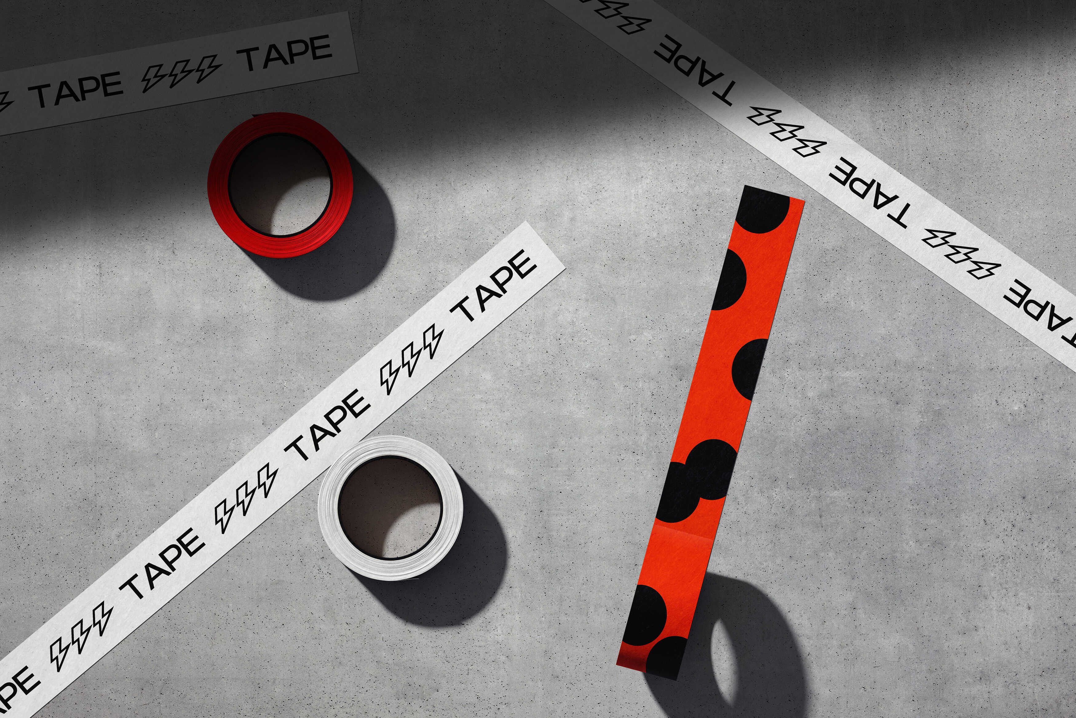 Rolls of white and red tape with printed graphics arranged on concrete floor