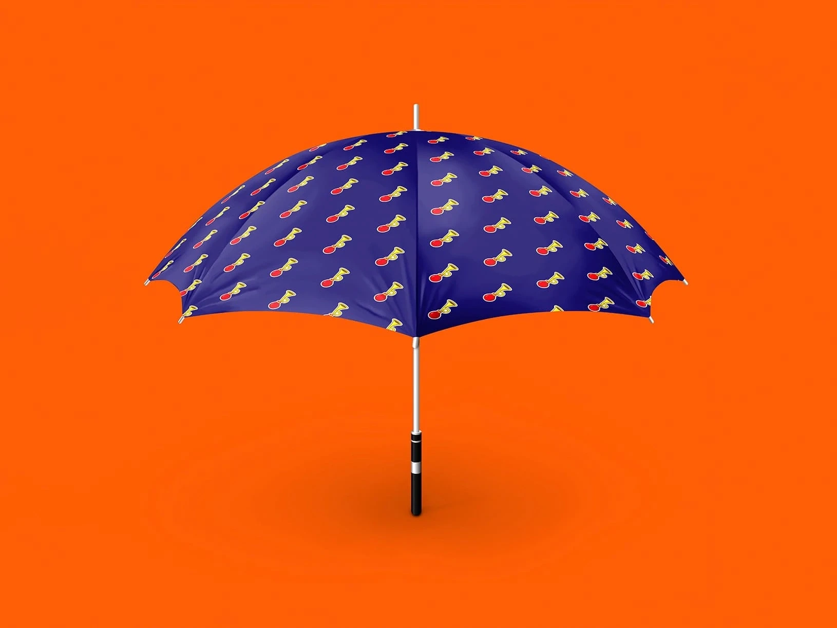 A navy blue umbrella with colorful repeating motifs stands open against a vivid orange background, creating a playful, cheerful contrast.