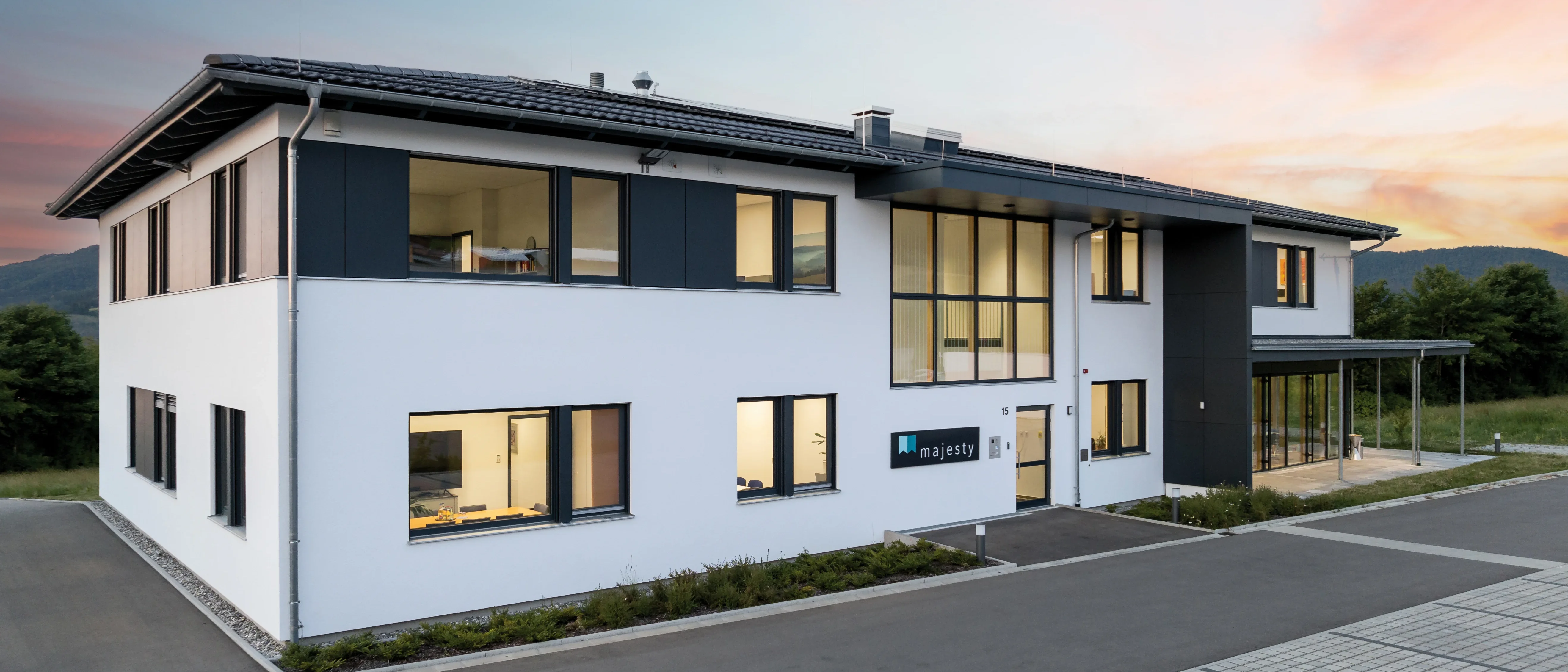 Blick auf modernes Bürogebäude mit Parkplatz davor.