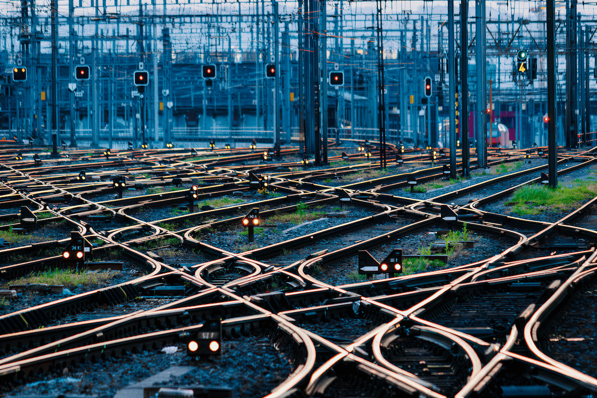 Railway switching yard at dusk with intersecting tracks and signal lights guiding unified routes