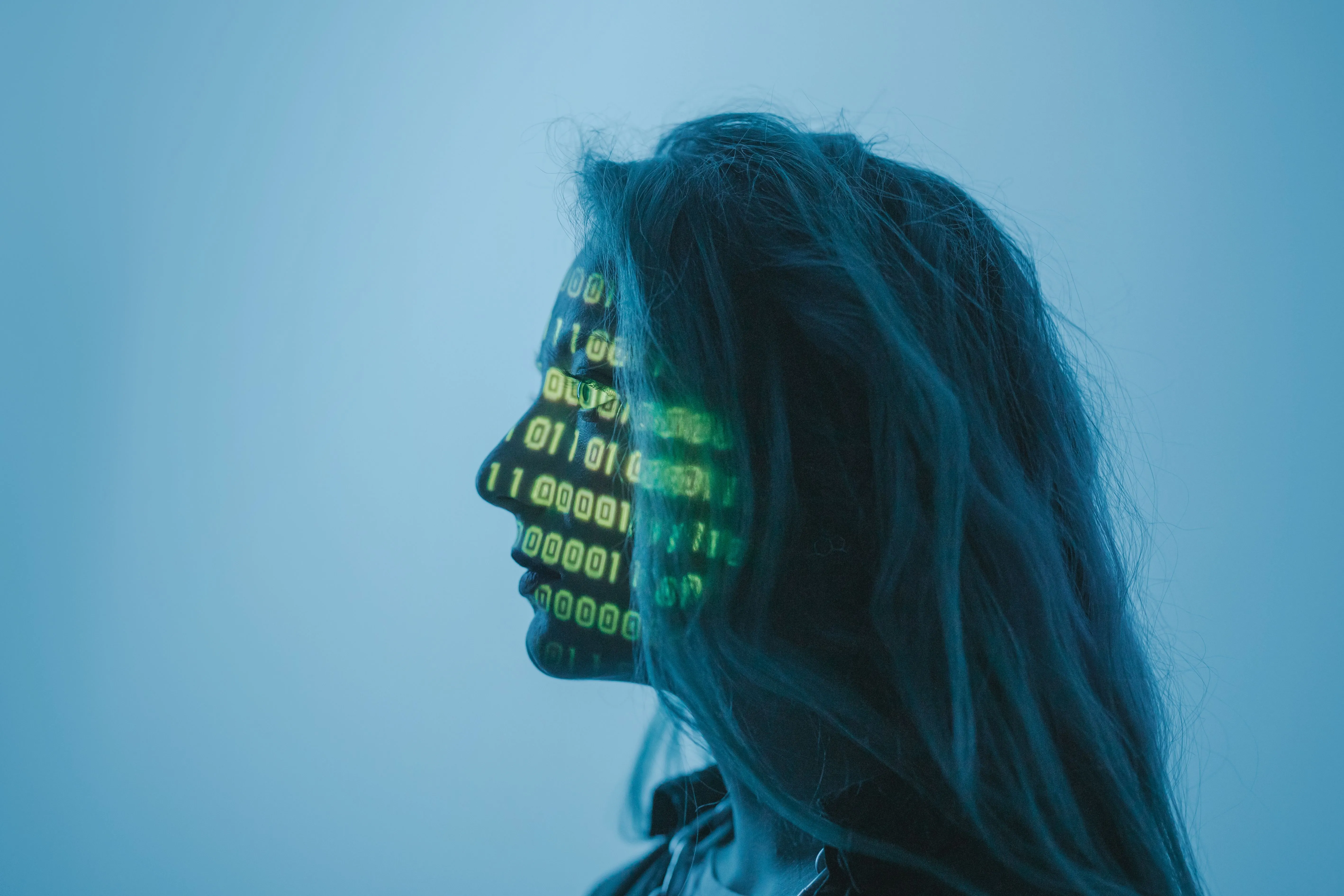 Profil eines Gesichts in blauem Licht, darauf projizierter grüner Programmcode.