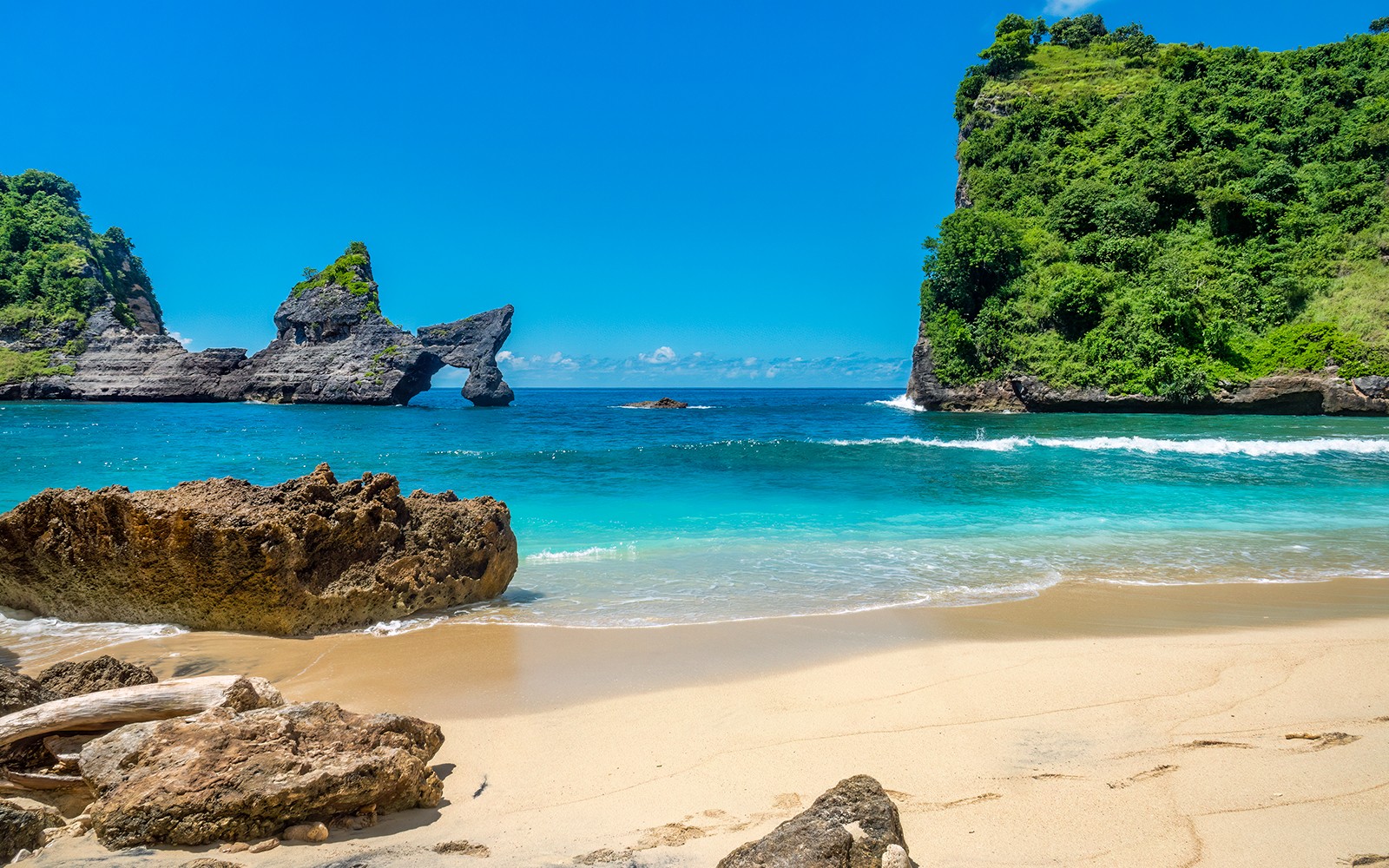 Turistas na Praia de Atuh, Nusa Penida, perto de penhascos únicos e águas azuis cristalinas.