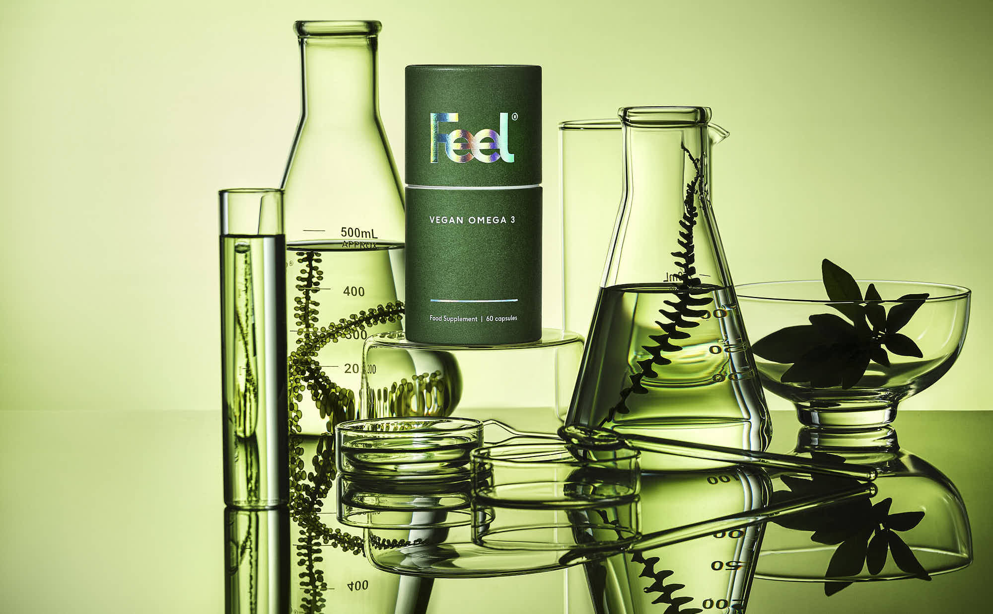 A collection of glass bottles and containers in various shapes, surrounded by green leaves on a light background.