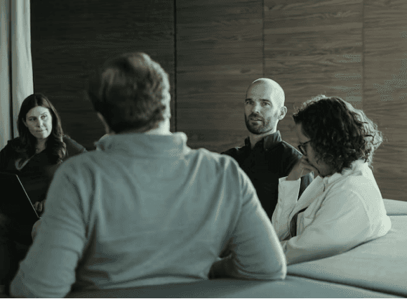 A group of four people sitting on a couch engaged in a lively conversation.