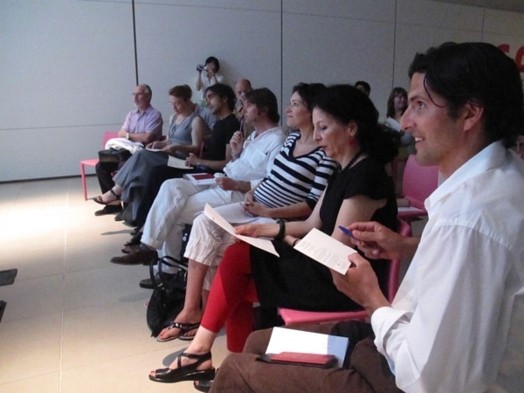A photo of a group of students listening to a lecture and taking notes.