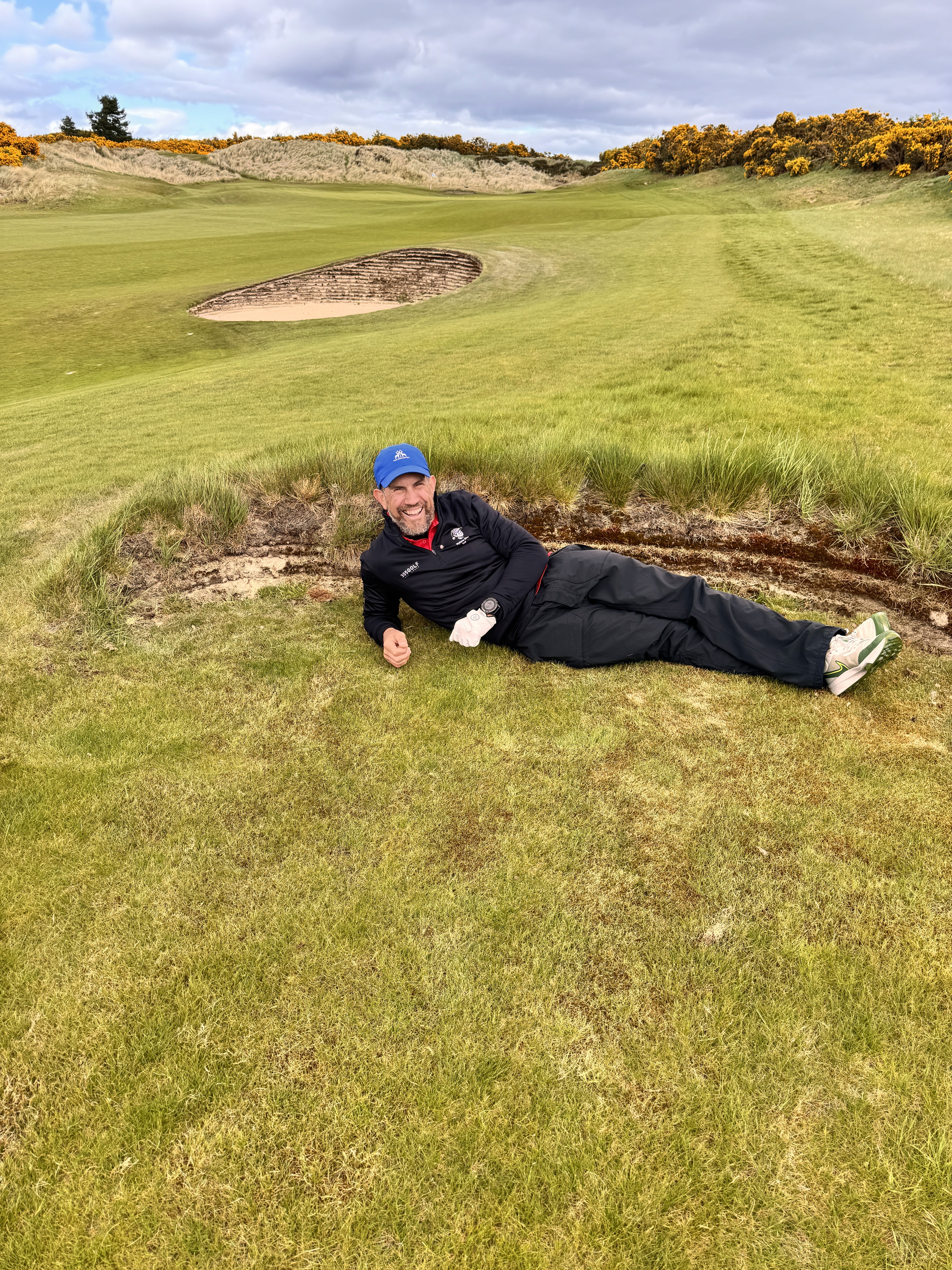 Nev Davies lying beside a bunker on a links golf course