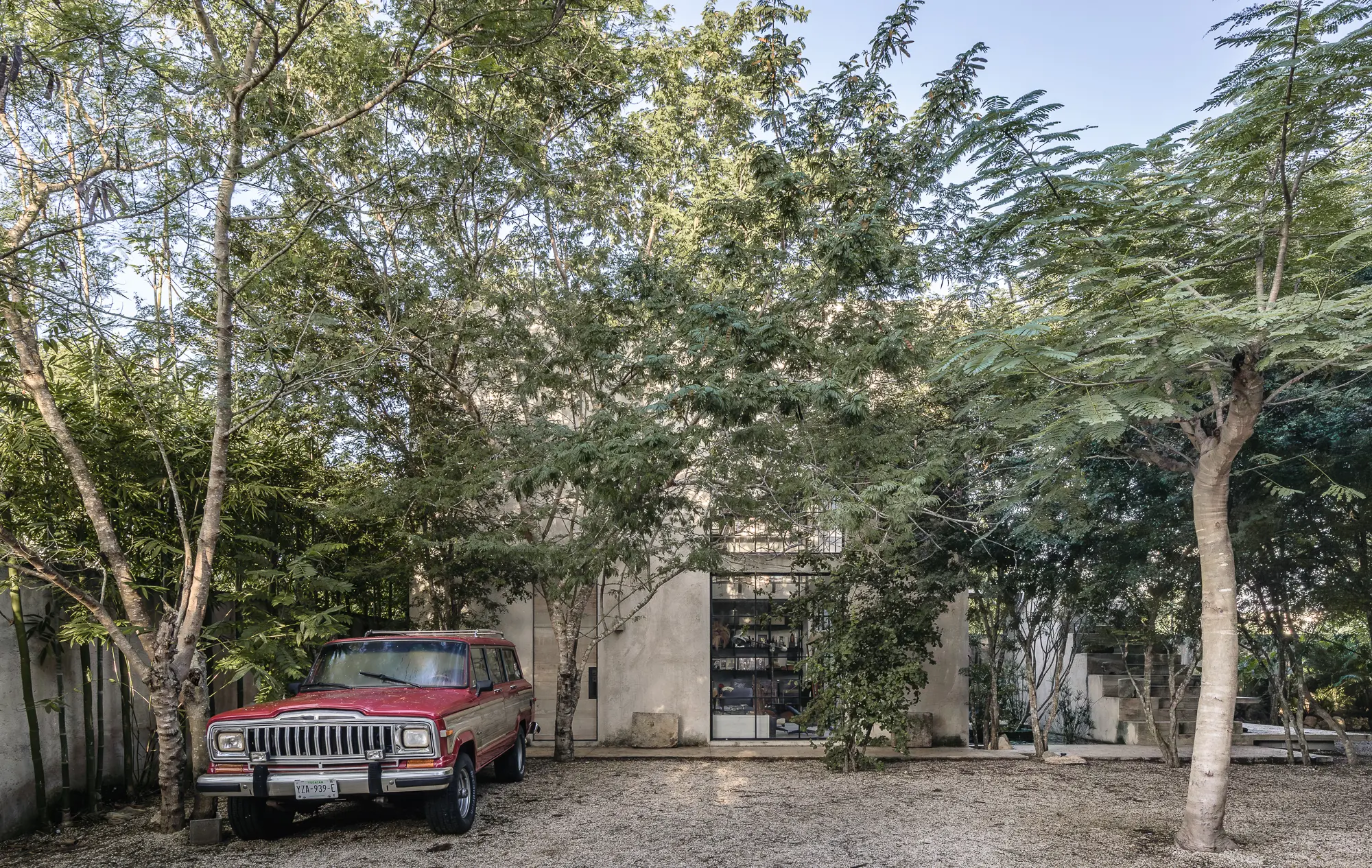 El Tigre - Edificio de concreto entre arboles, concreto aparente, gravilla