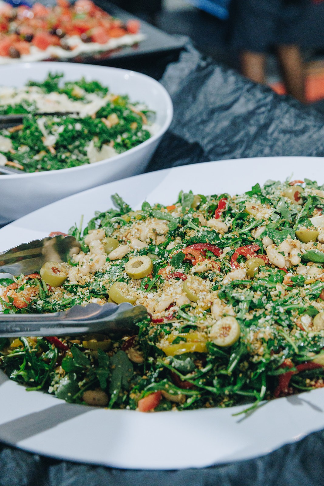 A close-up of a large bowl of mixed salad, surrounded by other bowls of food on a table.