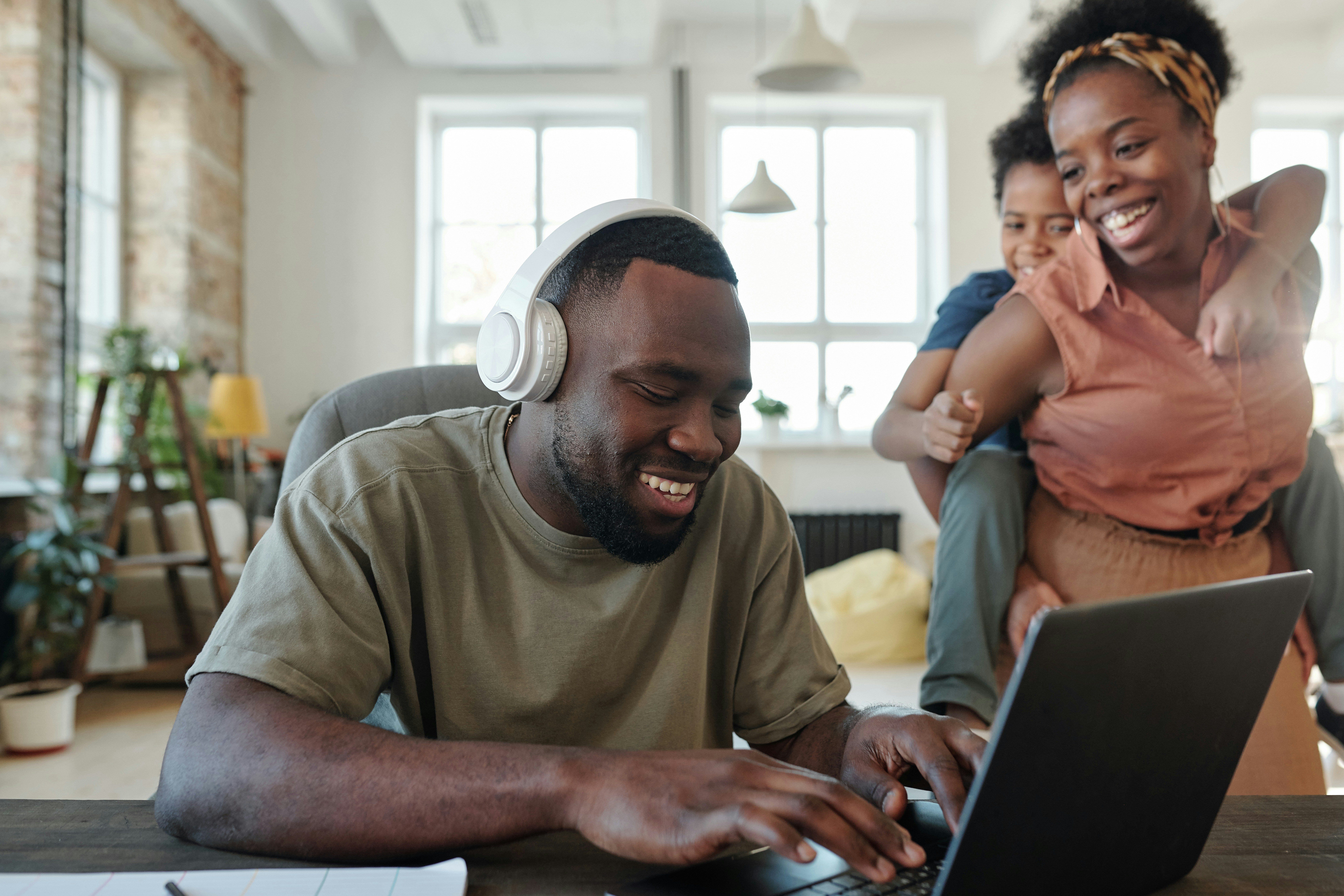 man types on computer while woman and young child on her back watch