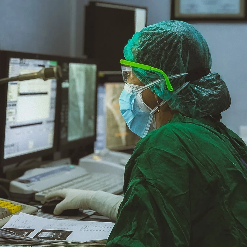 Photo of health worker in full PPE working at a computer