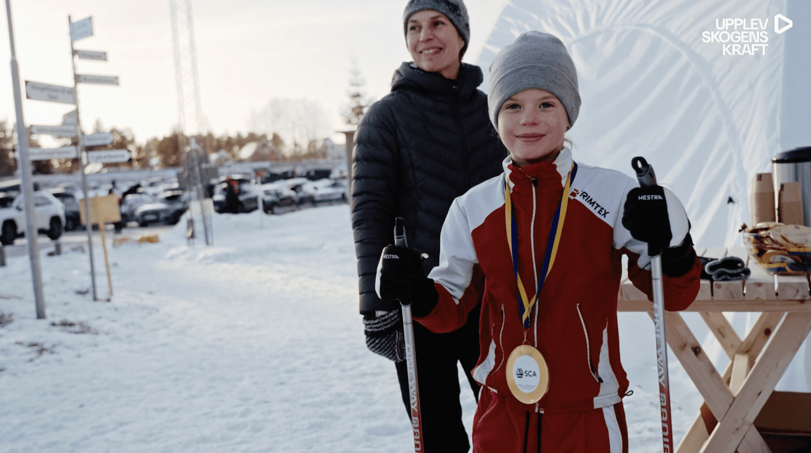 Ett barn i skidutrustning med en medalj runt halsen