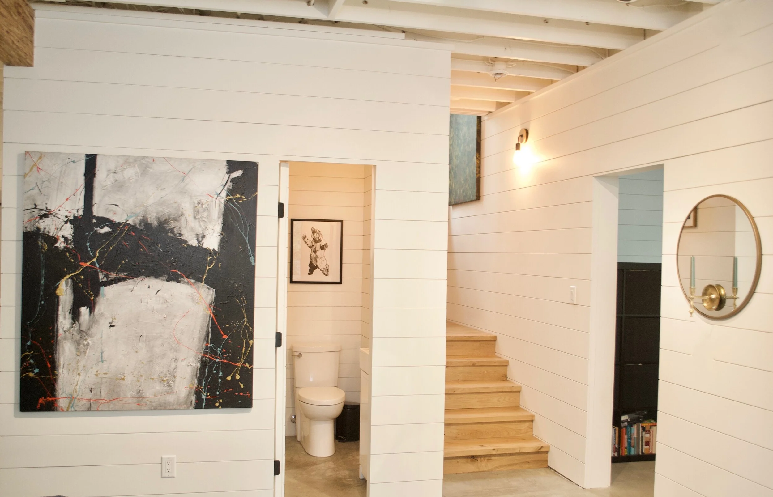 Modern two-story home with large glass windows, warmly lit interiors, and a balcony. Surrounded by trees and a manicured lawn at dusk. Cozy ambiance.