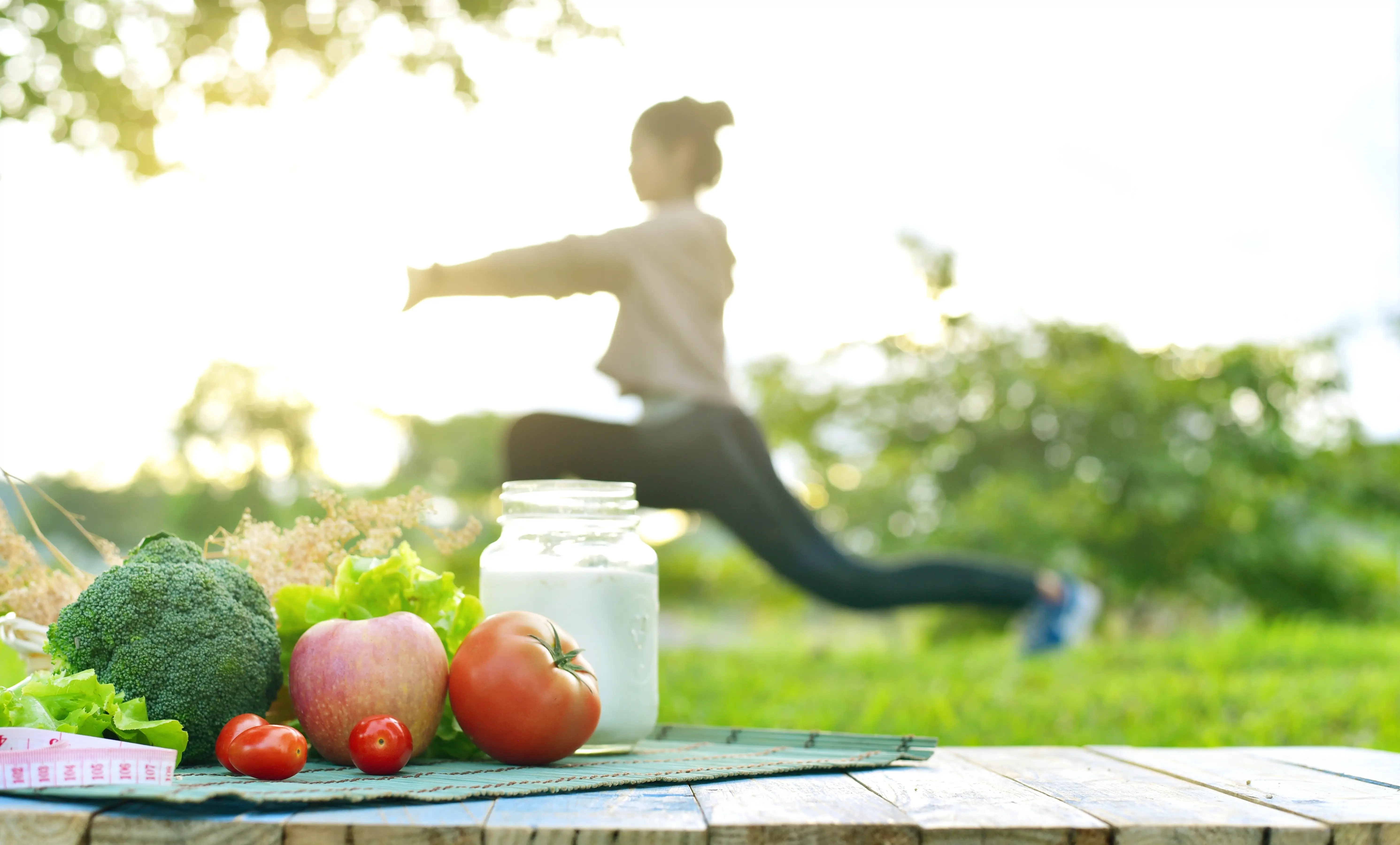 Mujer practicando bienestar integral con yoga y alimentación saludable al aire libre