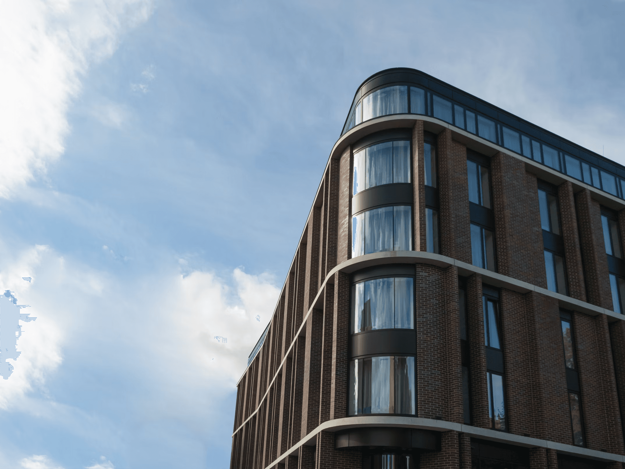 A modern brick building with blue sky and clouds in the background