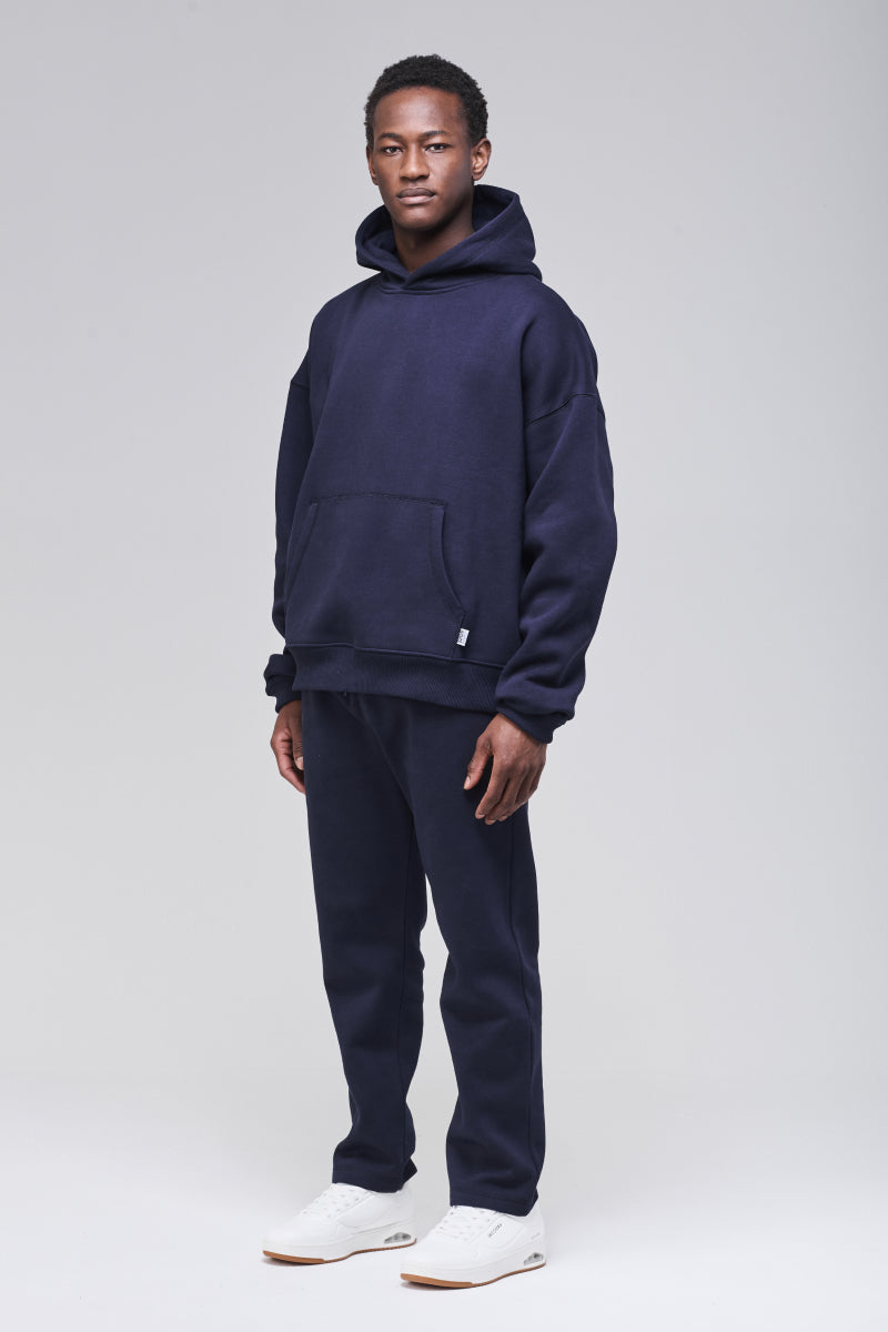 Male model wearing navy boxy hoodie in heavyweight fabric, full figure