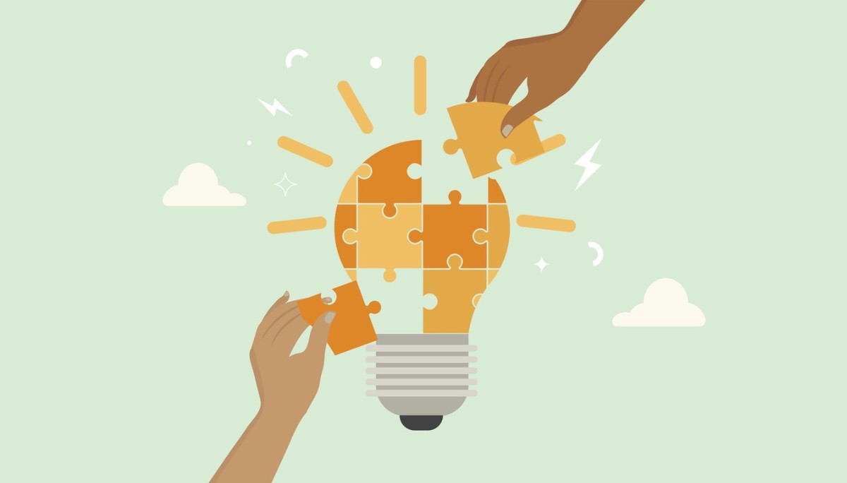 Illustration of a light bulb made of puzzle pieces being assembled by two hands—symbolizing collaborative thinking and problem-solving skills evaluated in interview questions.