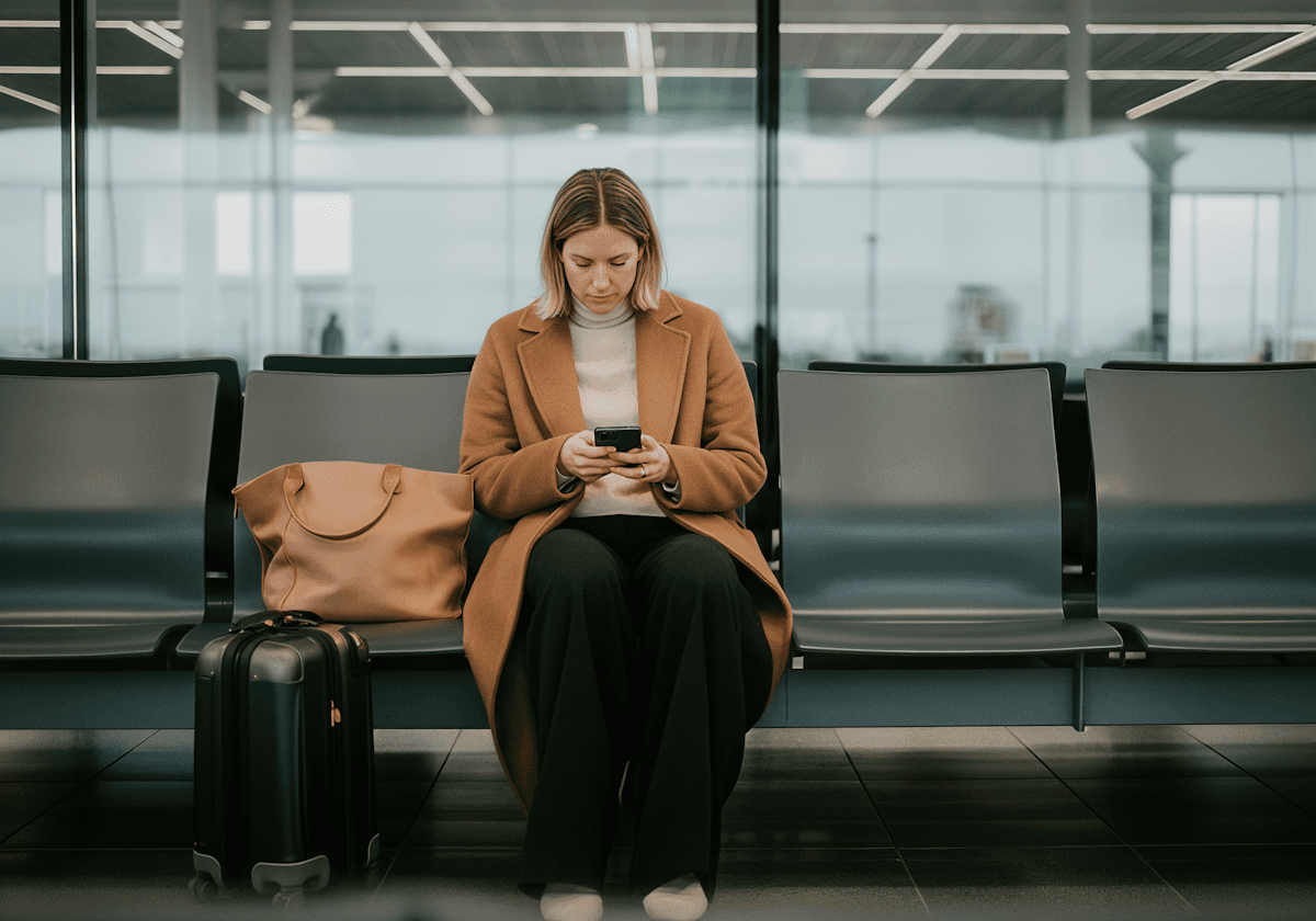 Woman in coat waiting at airport with luggage