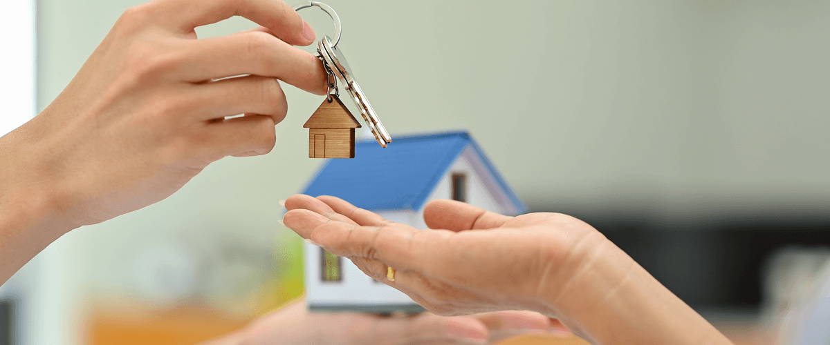 A  person's hands holding a model house and a set of keys, representing the advantages of YouTube videos for real estate companies.