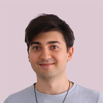 Portrait of a laughing person with curly hair wearing a white shirt
