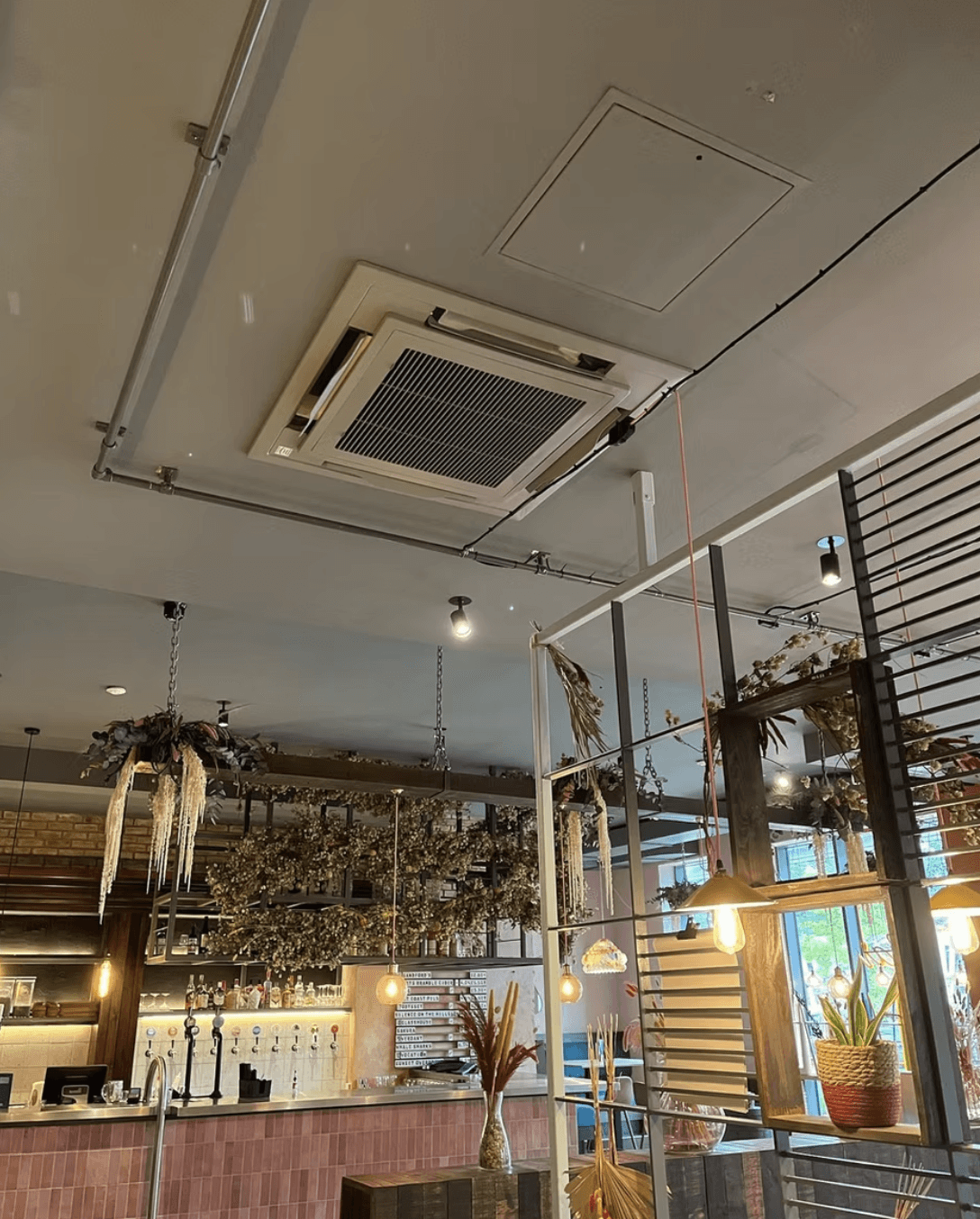 Modern kitchen with a wooden dining table, white chairs, and a hanging light fixture above.