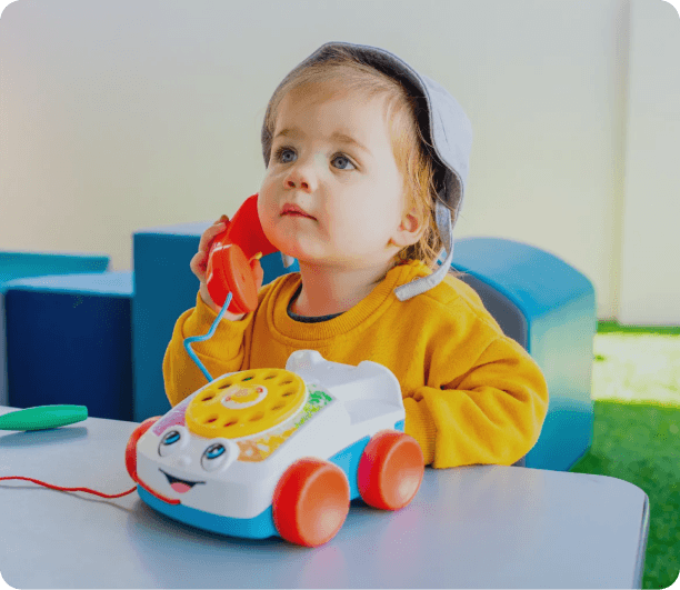 Toddler playing with a toy telephone during indoor learning time at Kaleidoscope Kids Redbank childcare centre.