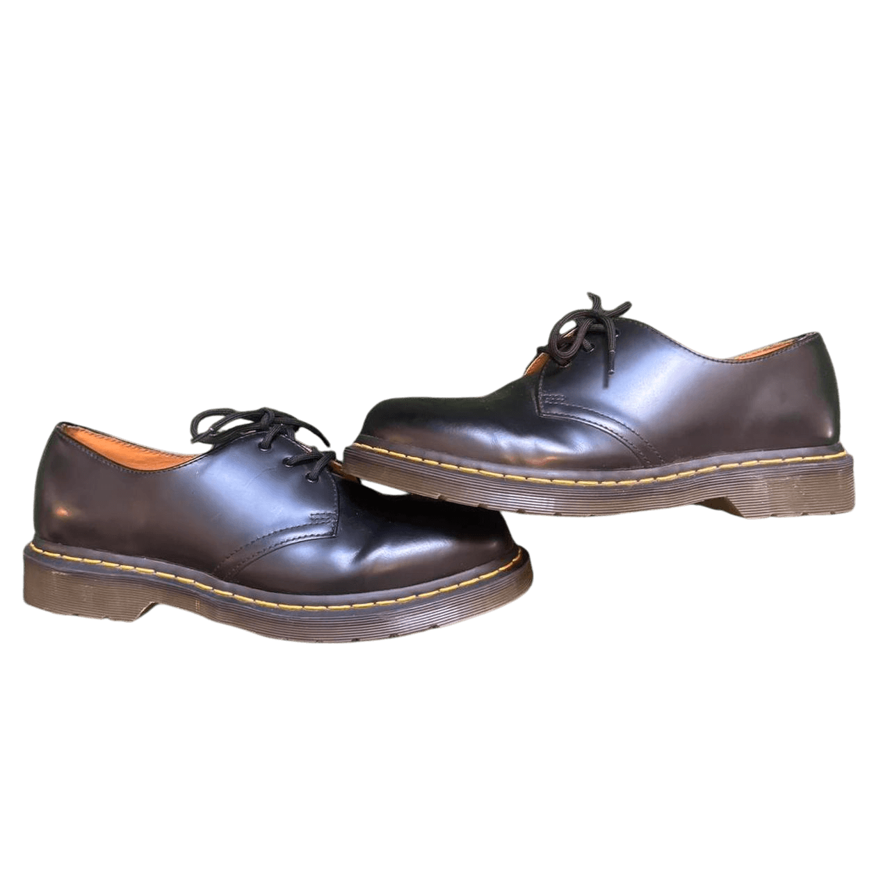 A modern green chair with a curved design and dark wooden legs against a dark background.