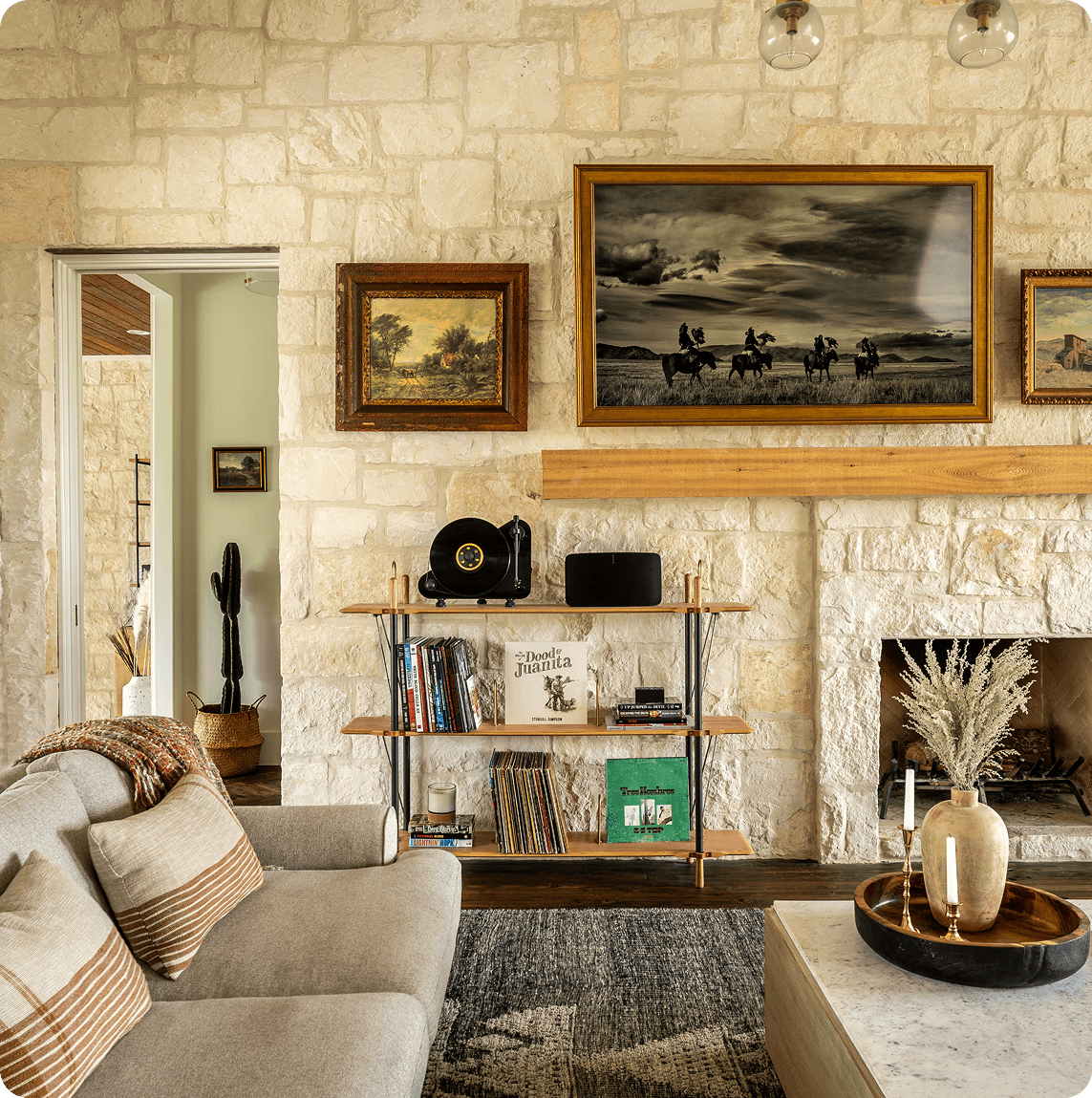 Modern farmhouse living room with plaid upholstered chairs, exposed wood beams, and large windows overlooking hill country