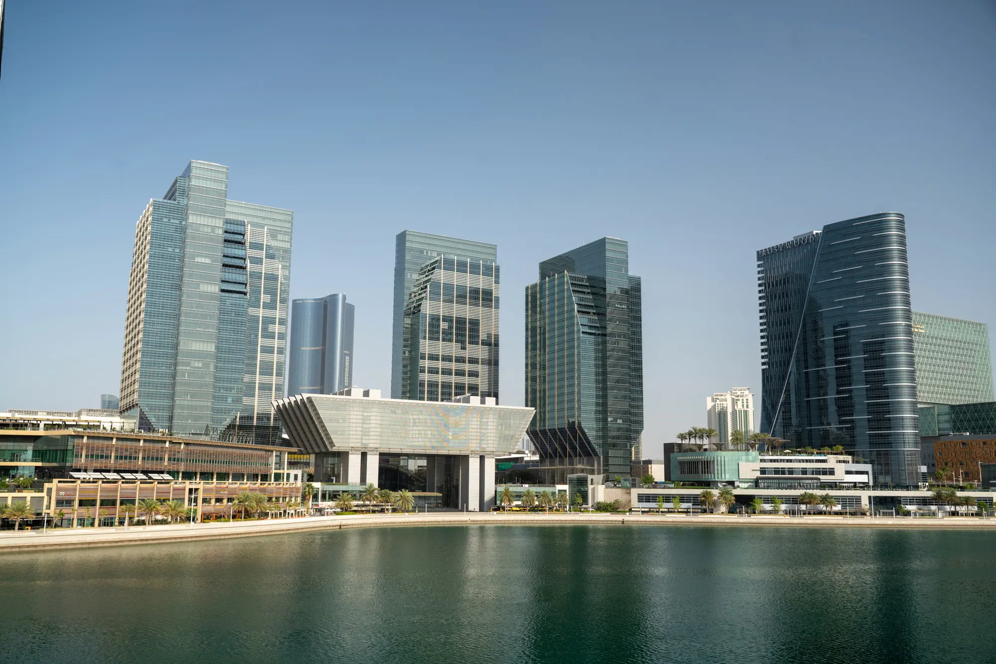 لقطة جوية لأفق أبوظبي، تتضمن عنواناً عن المناطق الحرة أبوظبي ودليل استكشاف الخيارات التجارية.