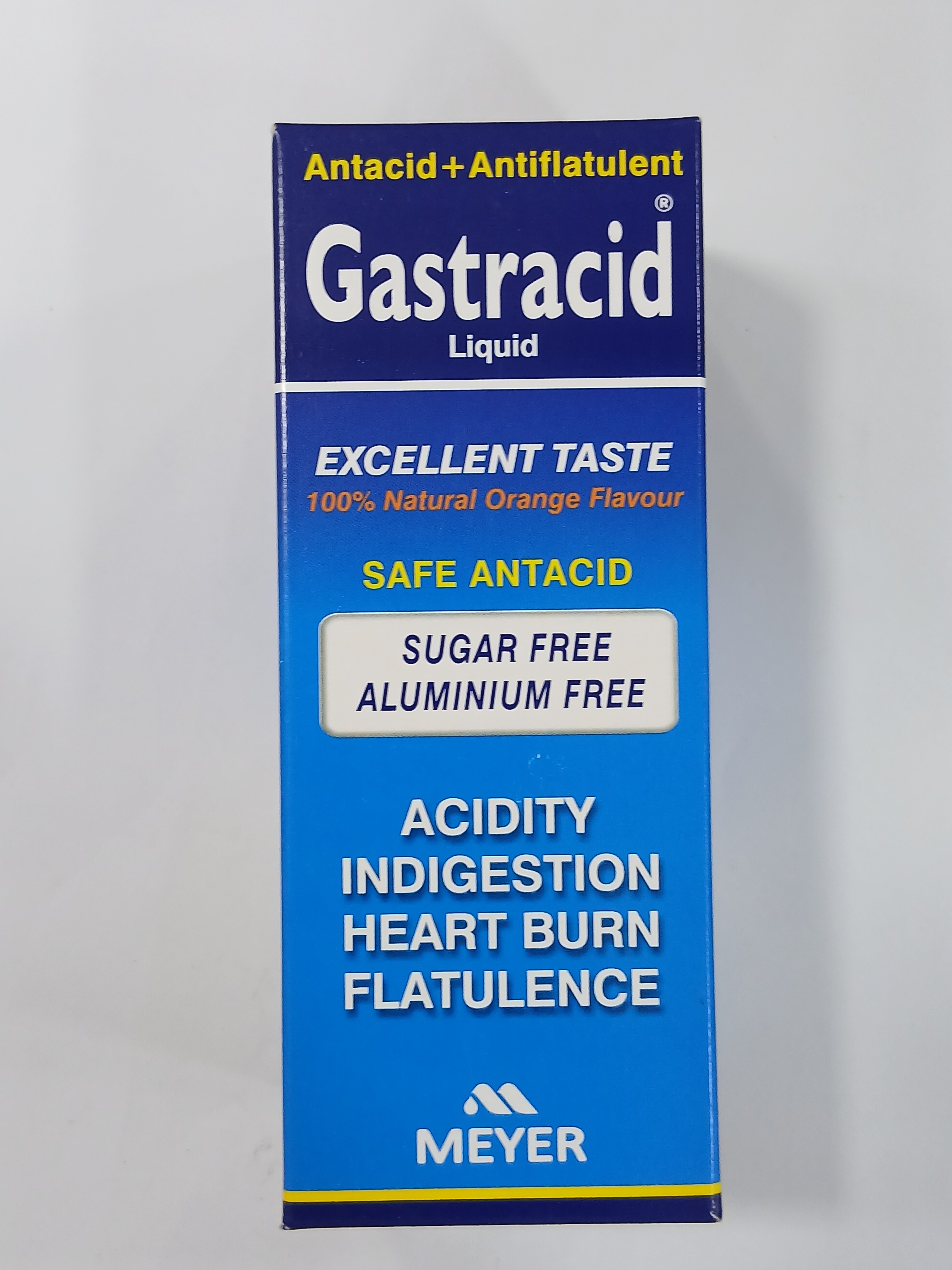 A vertical blue and white cardboard box packaging displays text promoting an antacid and antiflatulent liquid with claims of excellent taste, sugar-free and aluminum-free features, and mentions of uses for acidity, indigestion, heartburn, and flatulence.