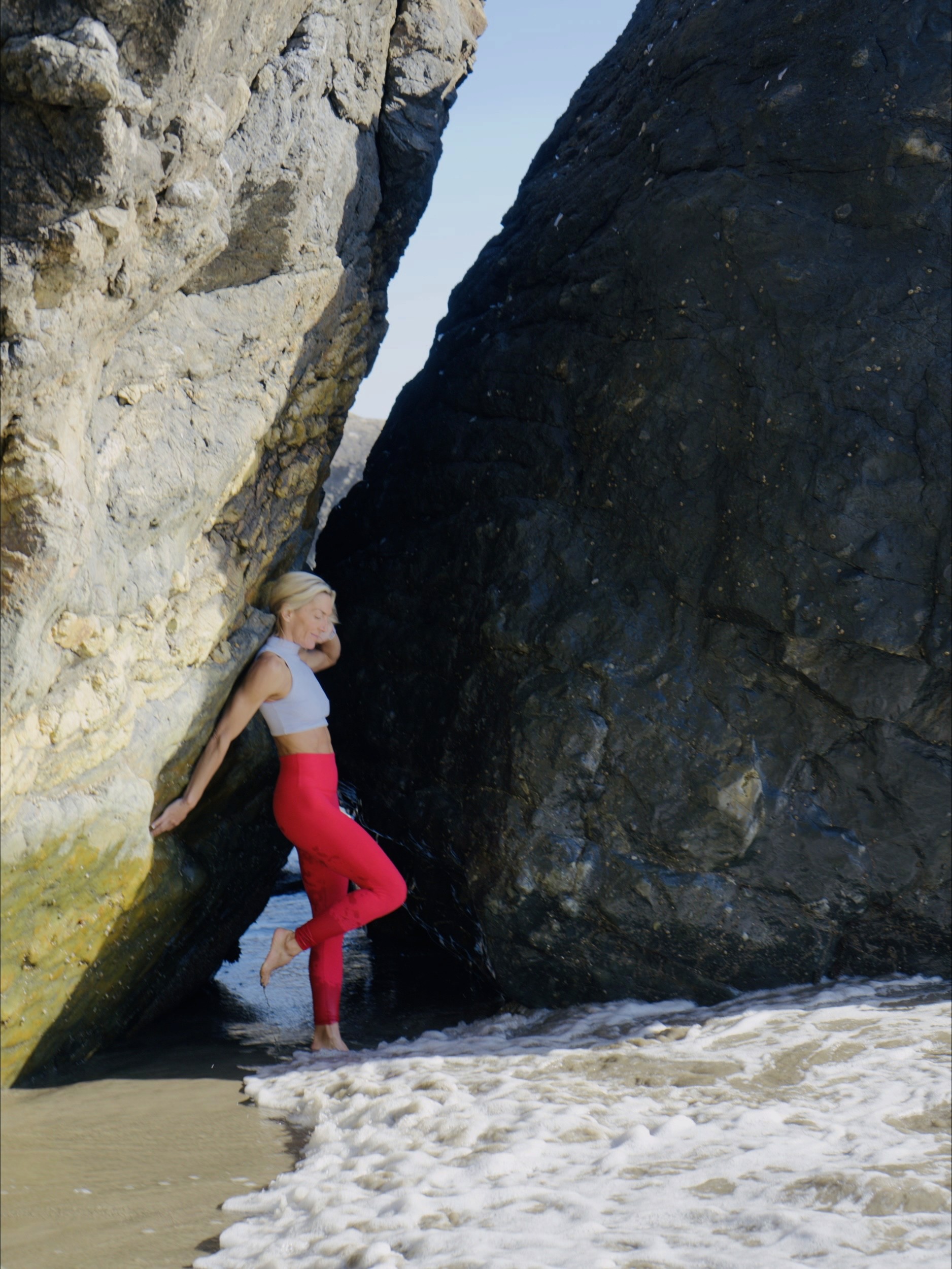 Coastal rock formation with Julie Locke standing at the water's edge