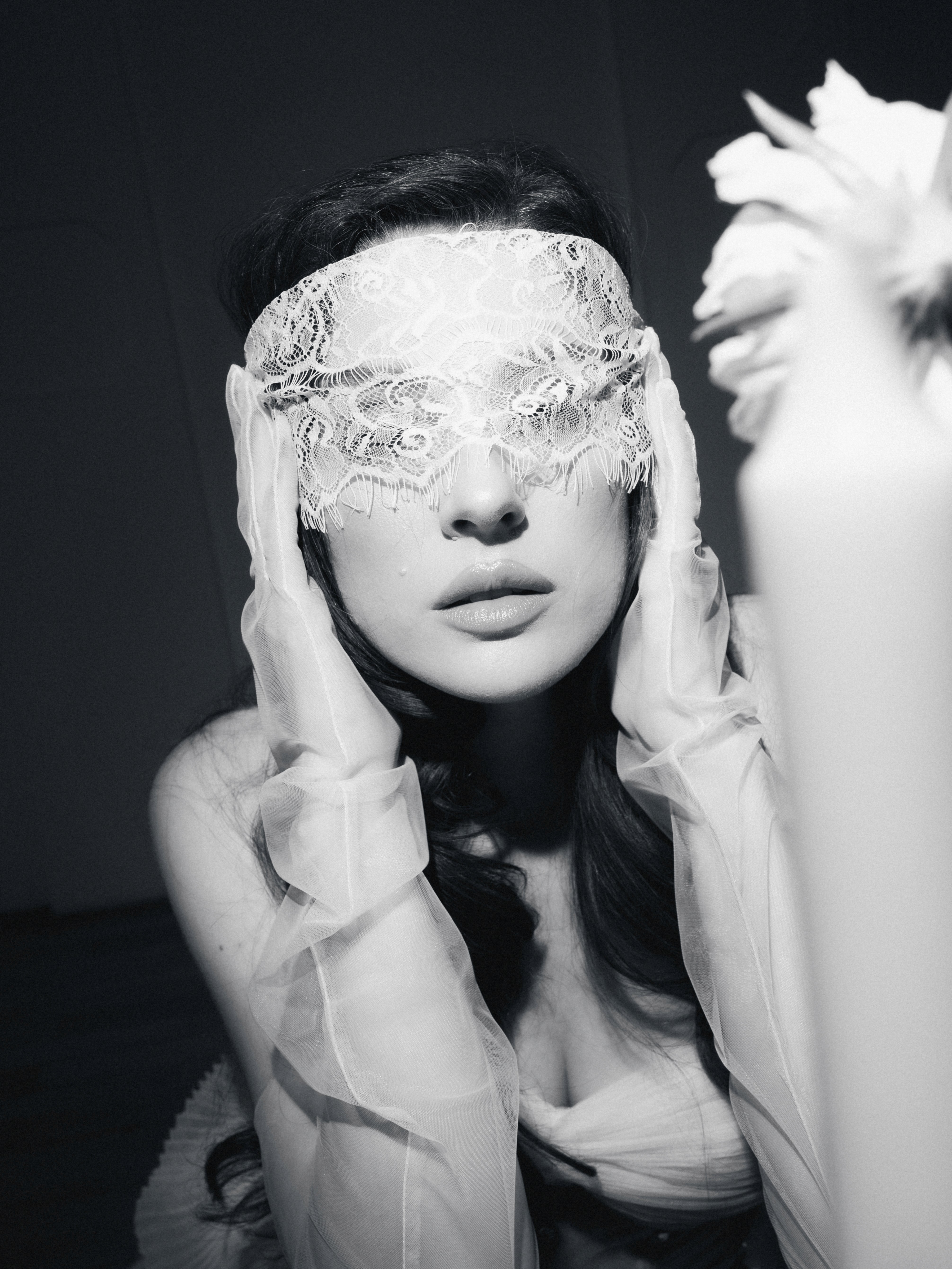 Prim-plan alb-negru cu mireasă purtând mănuși transparente și accesoriu artistic peste ochi, fotografie editorială de nuntă cu influențe high fashion și atmosferă cinematică, surprinsă într-un stil elegant și modern.