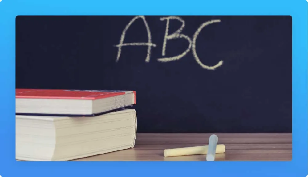 Two books, 2 chalk sticks and blackboard with ABC in the background