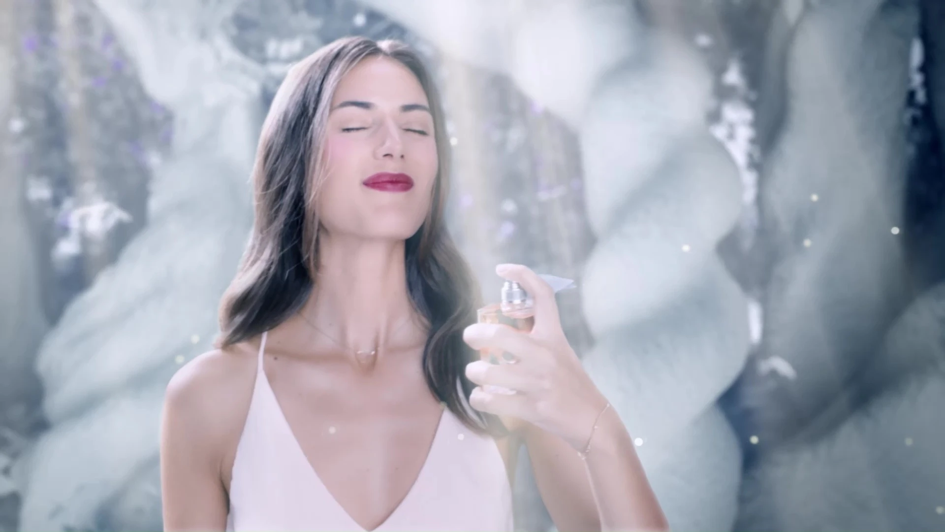 Woman spraying herself with perfume in a fantastical white porcelain forest