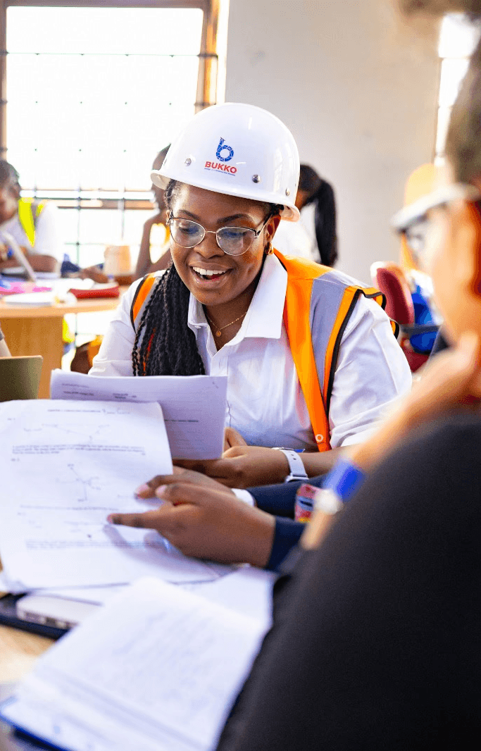 A student wearing a red uniform sits while holding a book in his hands