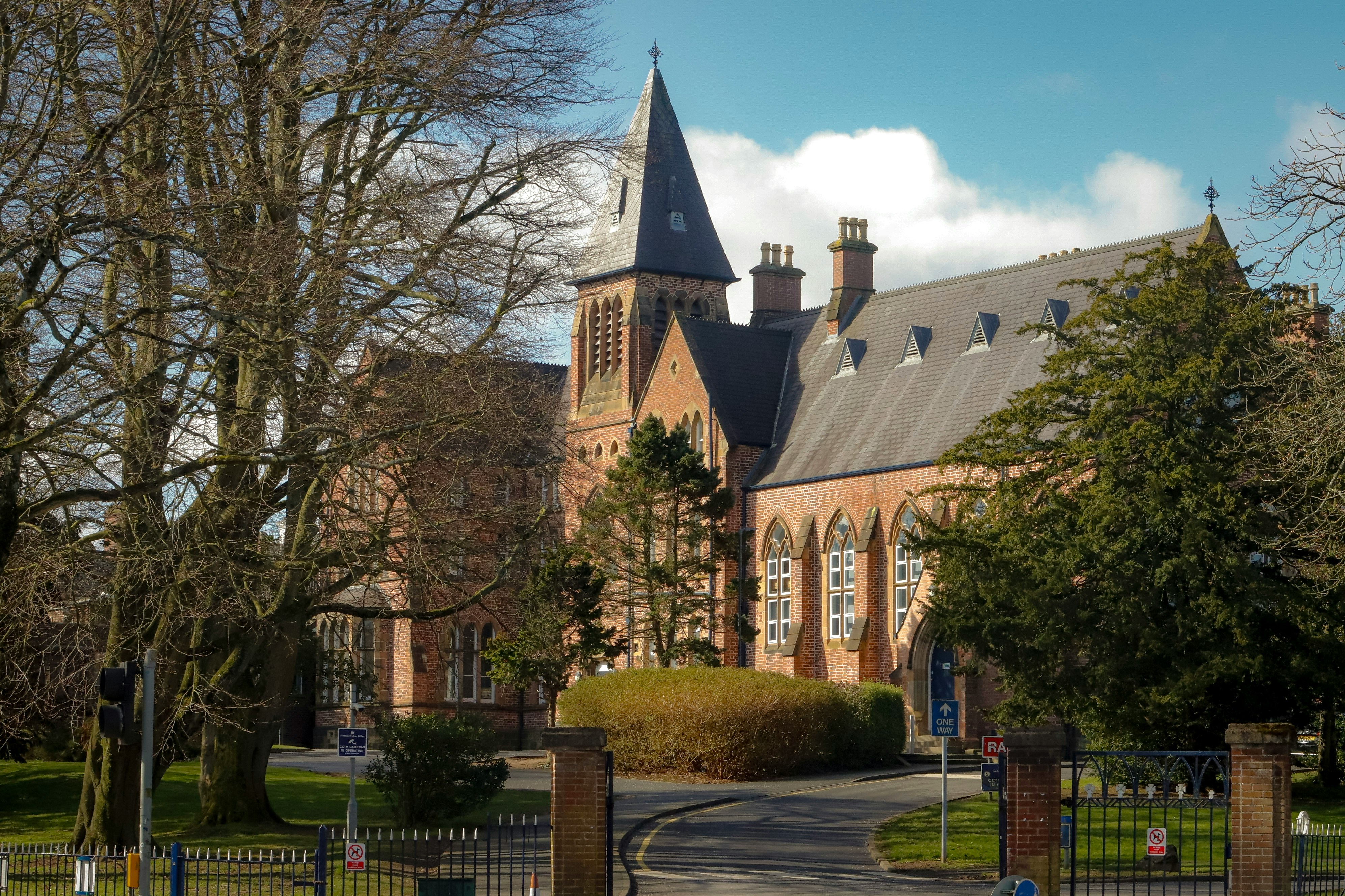 Historic brick building with a tall steeple under blue sky