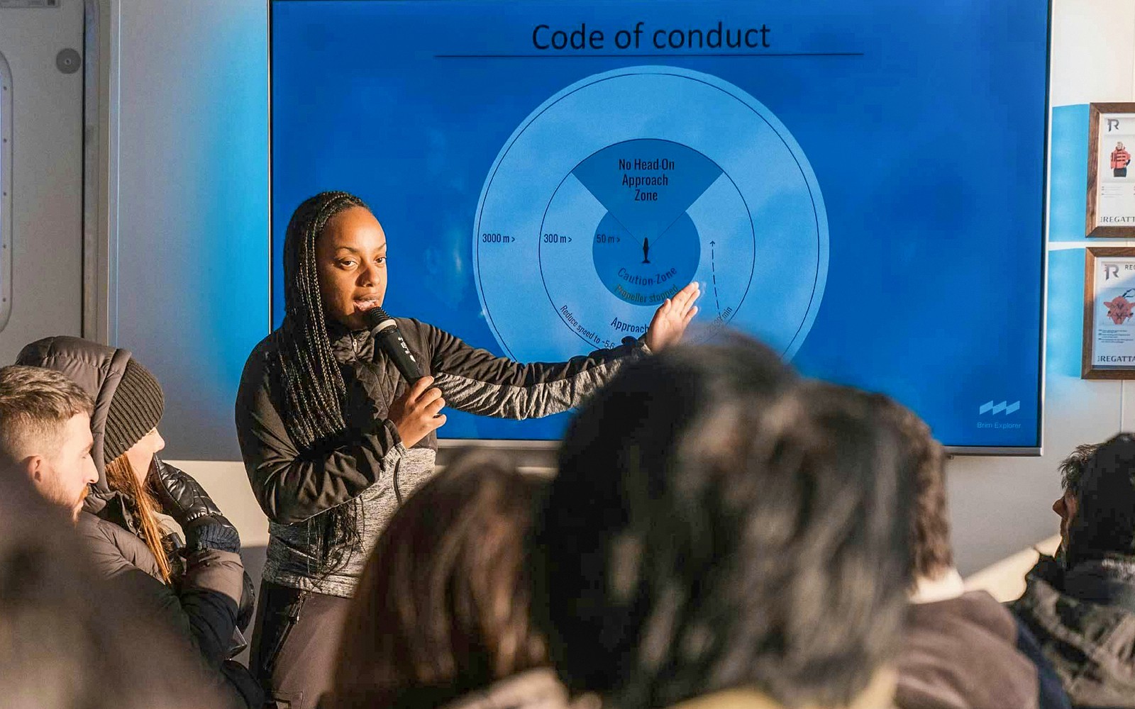 Female guide explaining whale watching code of conduct to tour group.