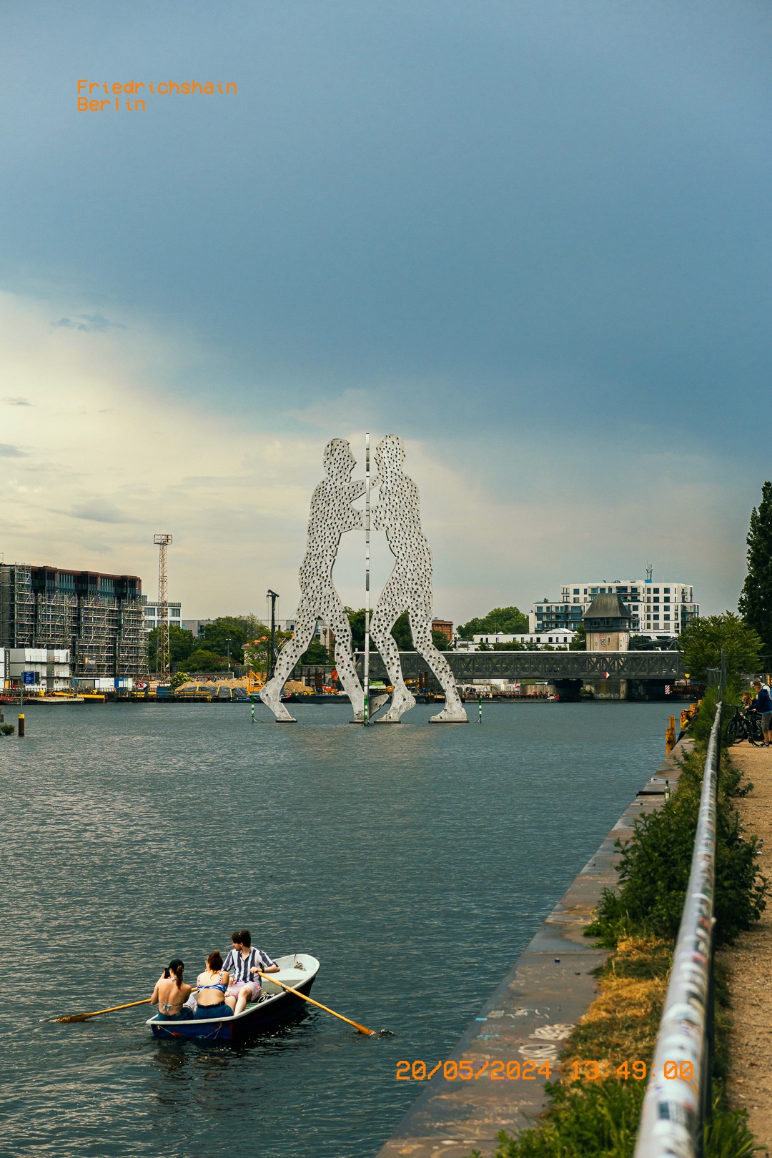 Molecule Man à Berlin sous un ciel nuageux, avec des rameurs profitant de l'eau.