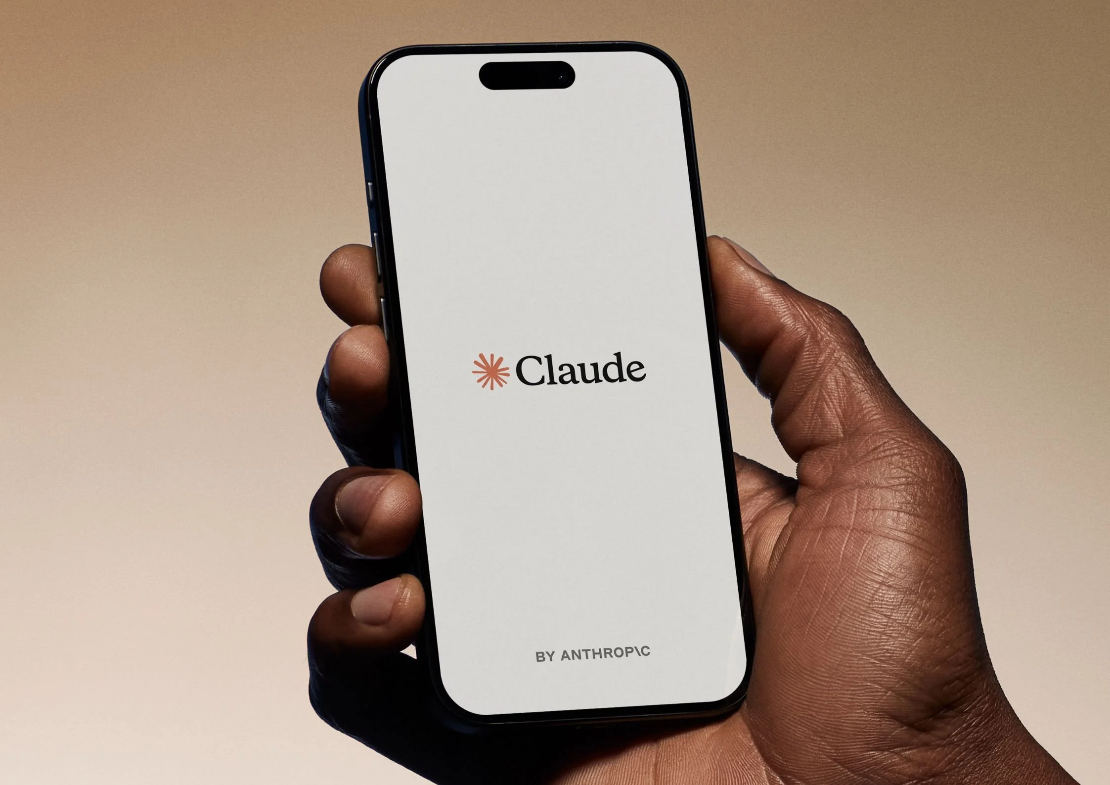 Hand holding a phone displaying the Claude by Anthropic app