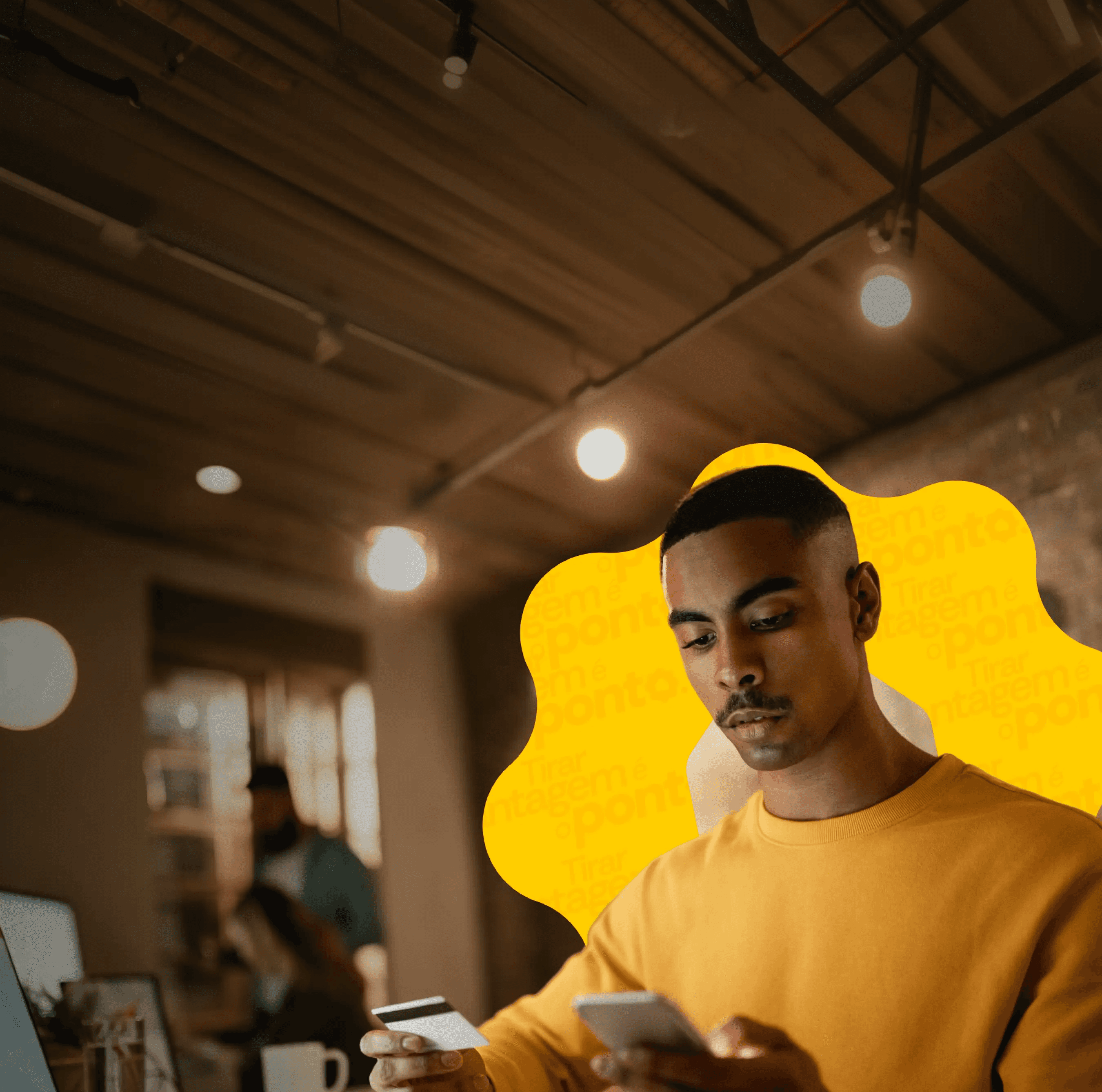 Homem jovem usando o celular e segurando um cartão de crédito